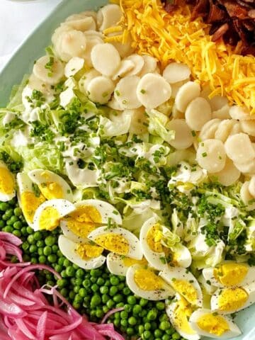 Salad ingredients layered on a platter and garnished with chopped chives.