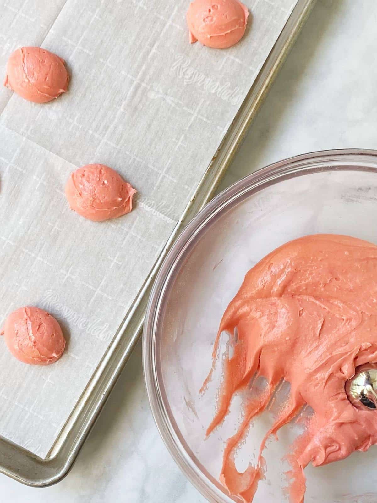 Cookie dough portioned onto a parchment paper-lined sheet pan.