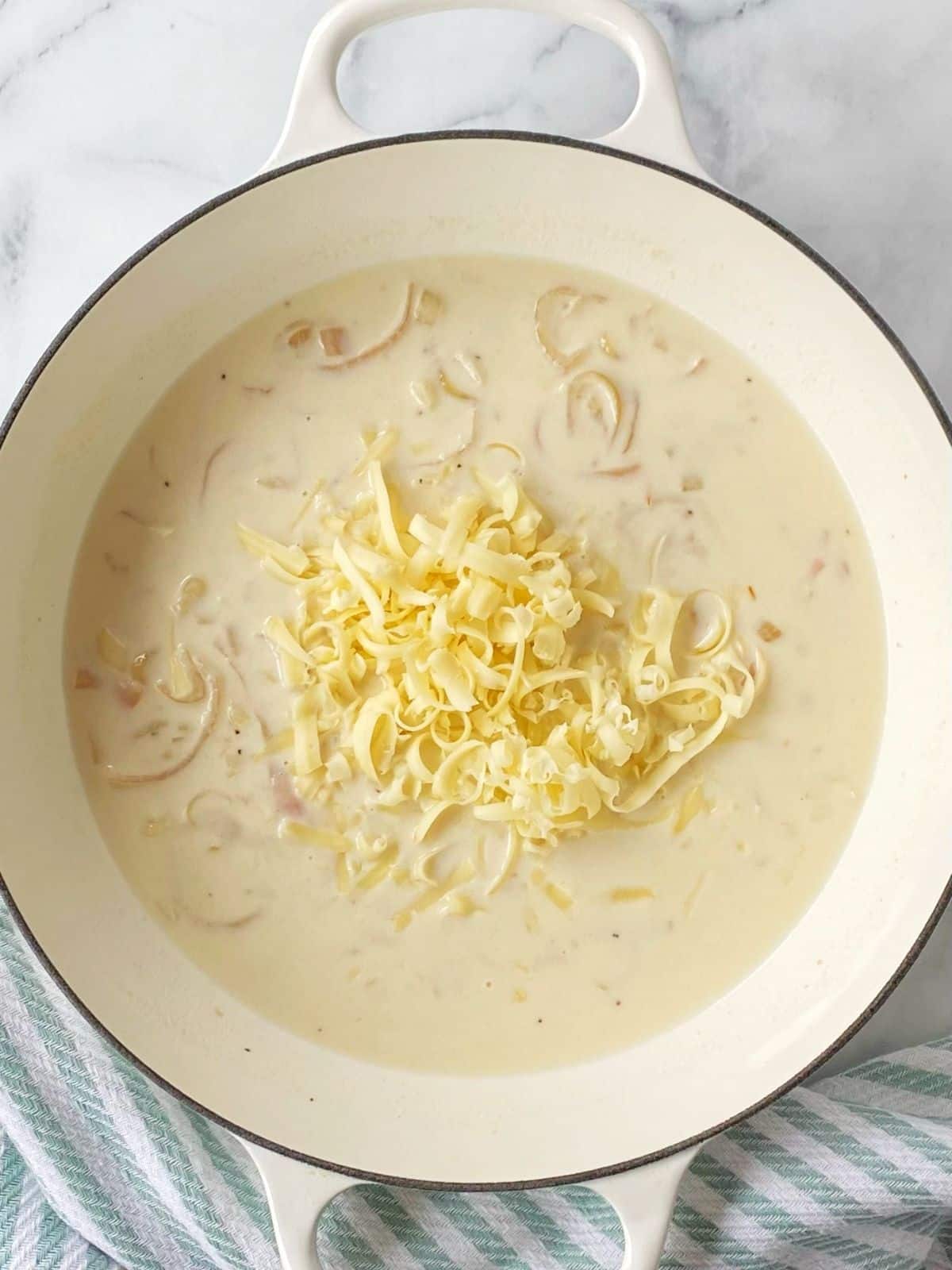 Adding cheese to the cream sauce.