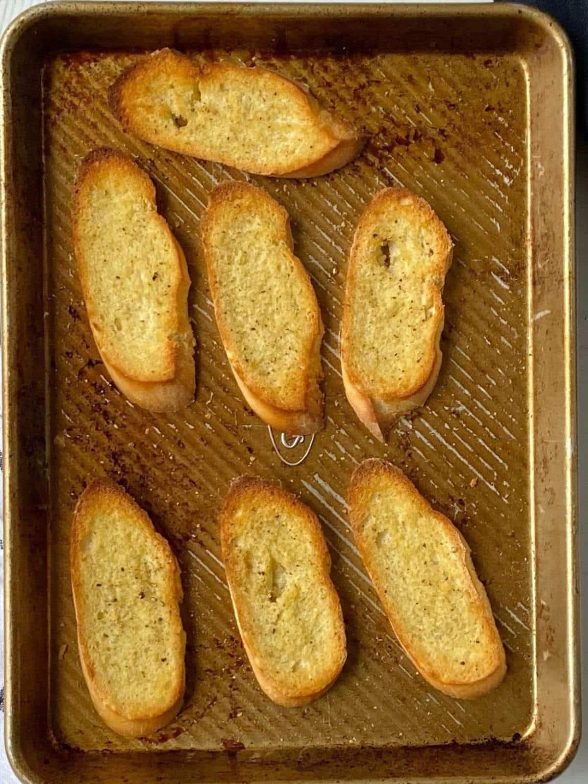 Toasted crostini on a sheet pan.