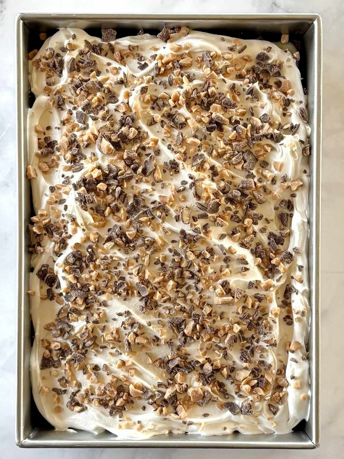 Cake garnished with Heath baking bits on top of whipped topping.