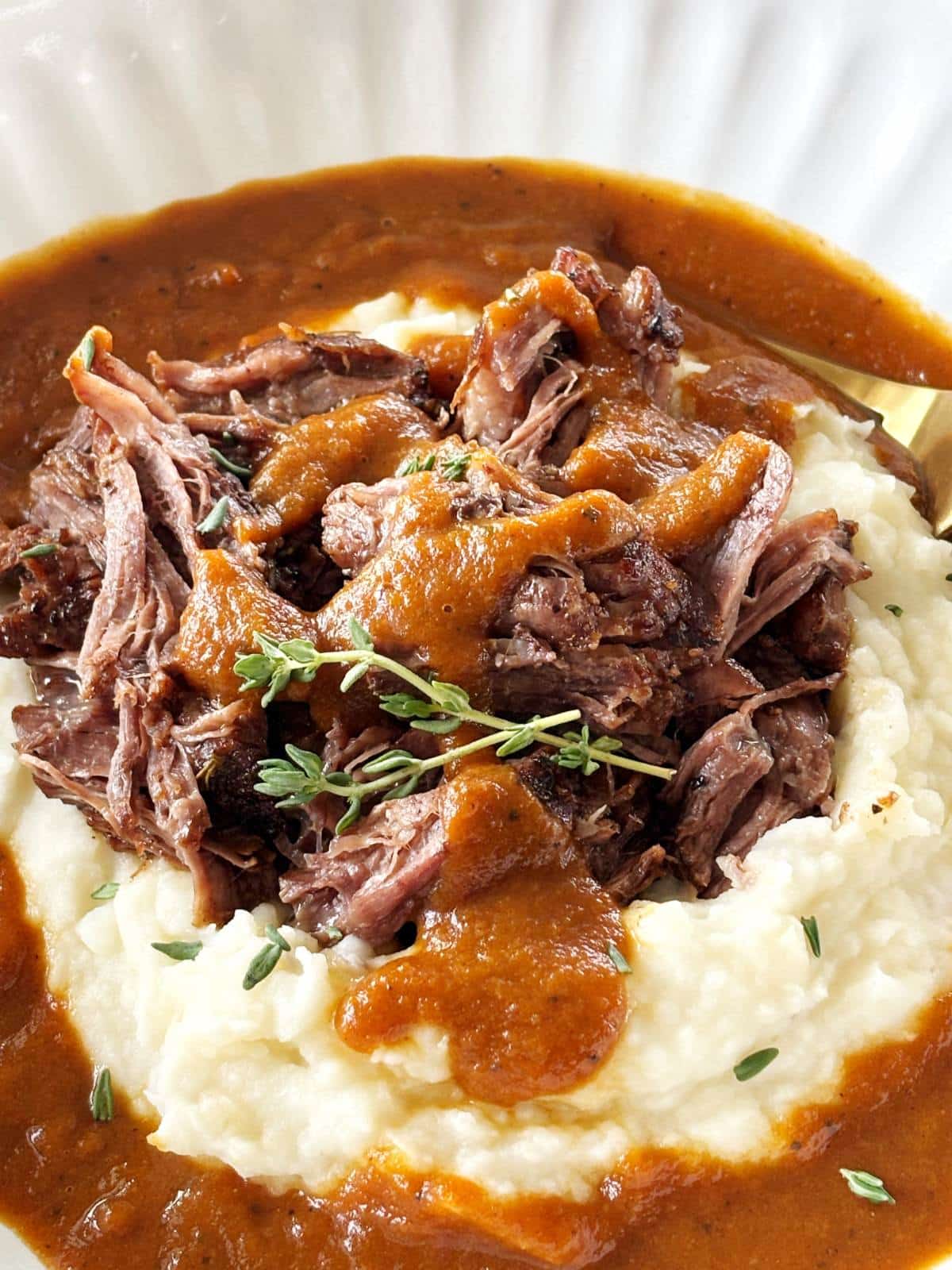 Shredded pot roast on top of mashed potatoes and gravy.
