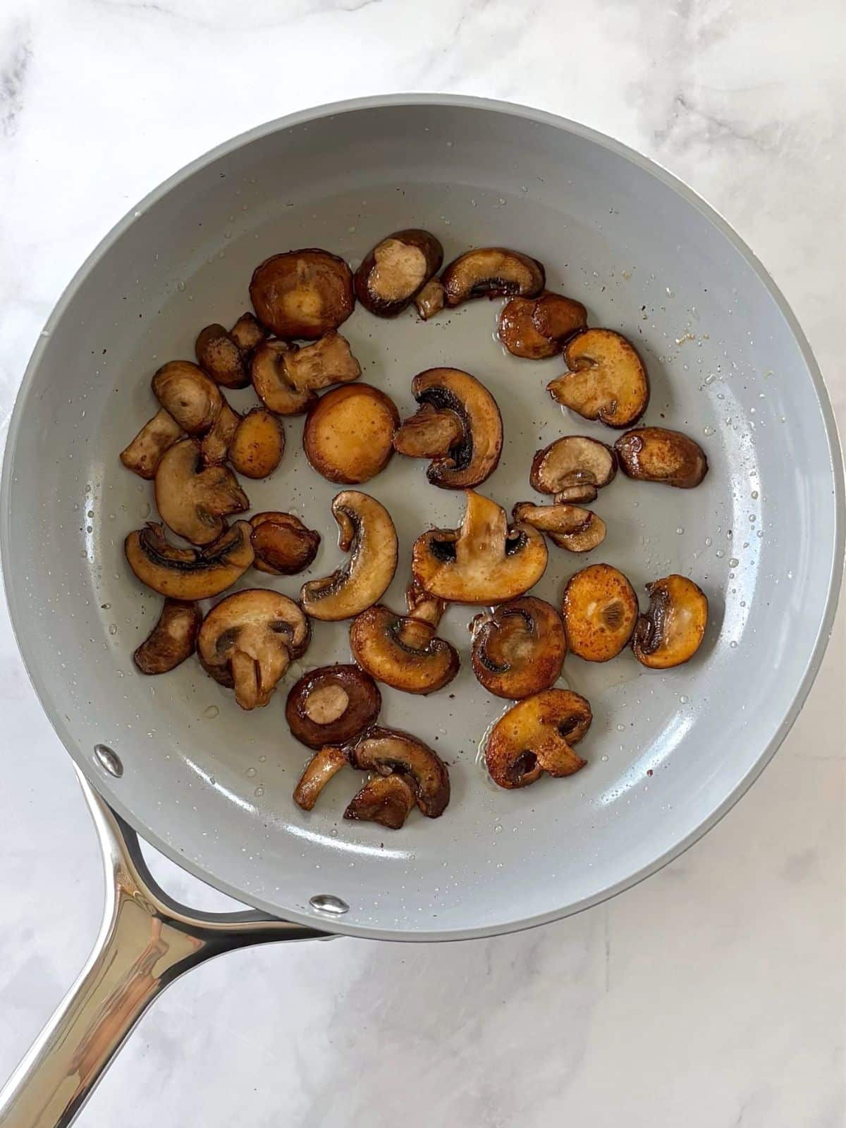 Mushrooms cooking in a skillet.