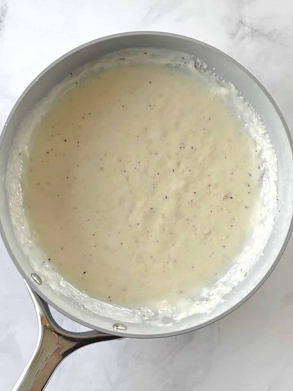 Cream sauce cooking in a skillet.