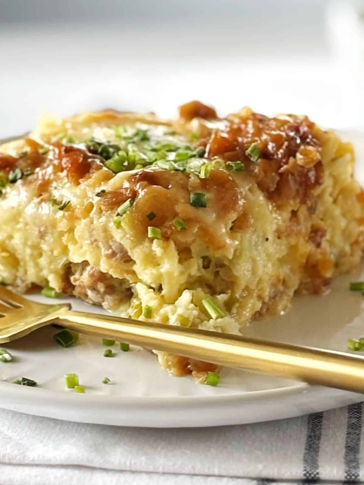 Plate with a serving of sausage casserole next to a fork.