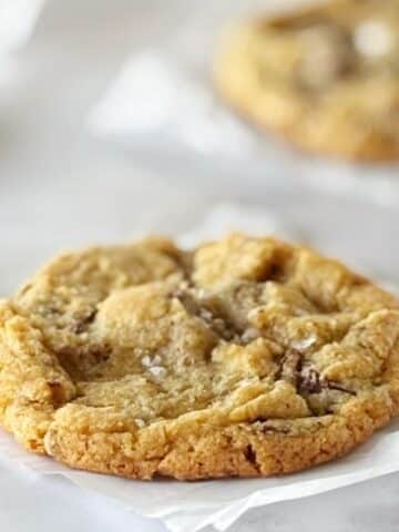 Cookie on a piece of parchment next to another cookie.