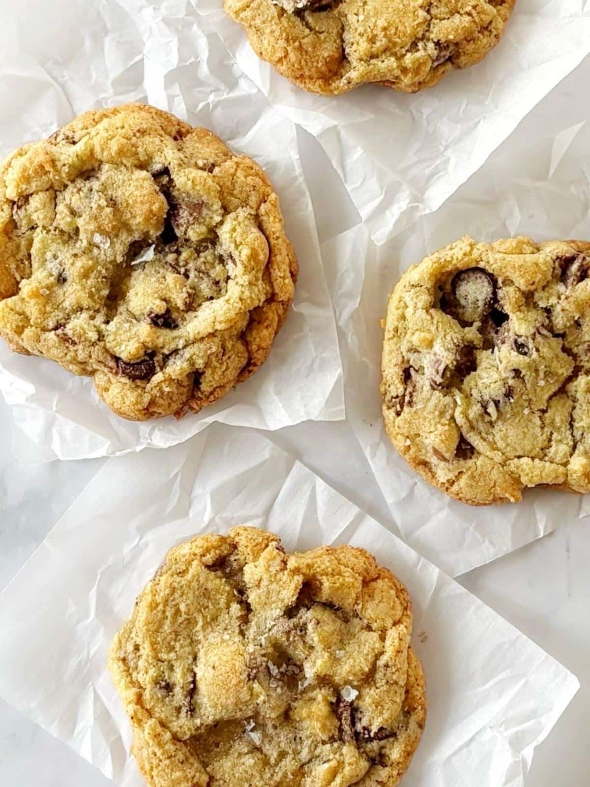 Cookies topped with flaky salt on parchment paper.