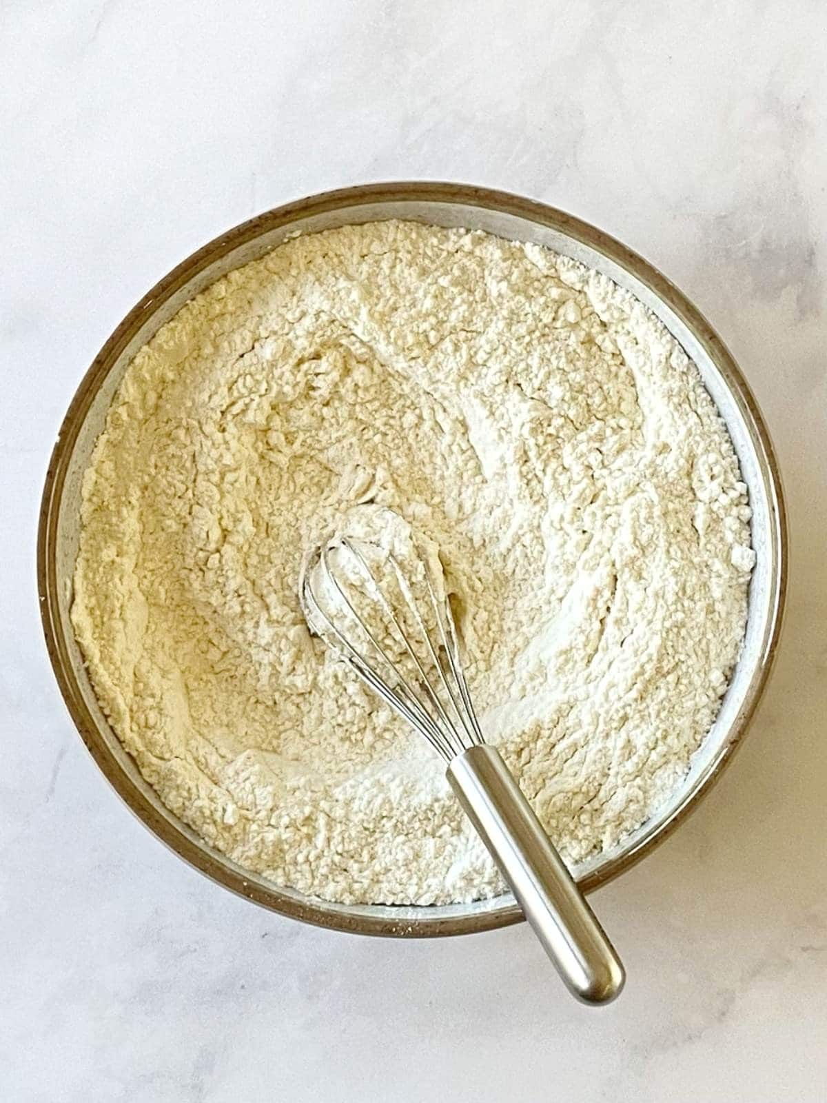 Flour, baking powder, baking soda, and salt whisked together in a bowl.