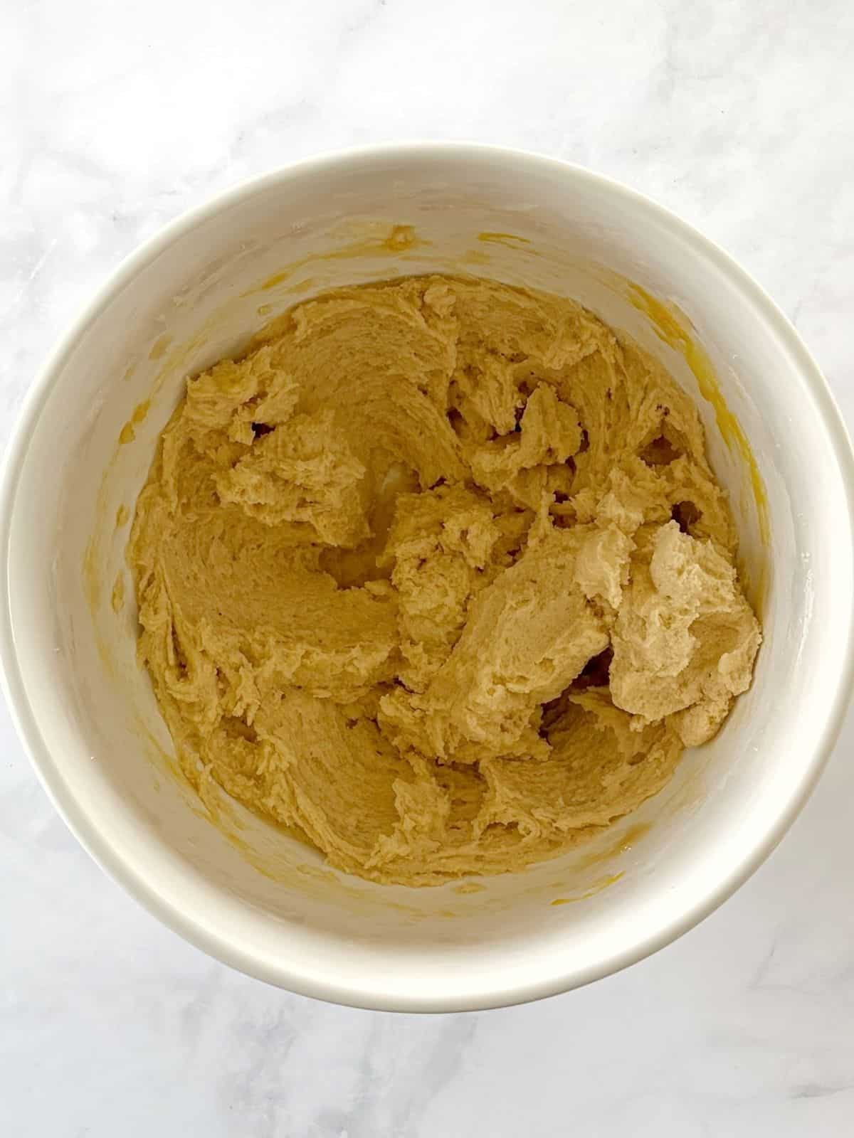 Butter and sugar mixture combined with eggs and extracts in a mixing bowl.