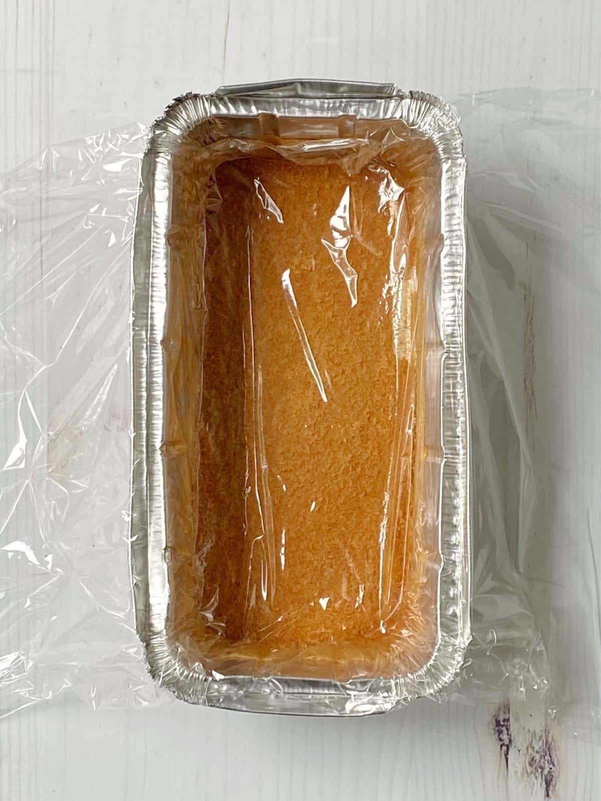 Cake pan lined with plastic wrap.