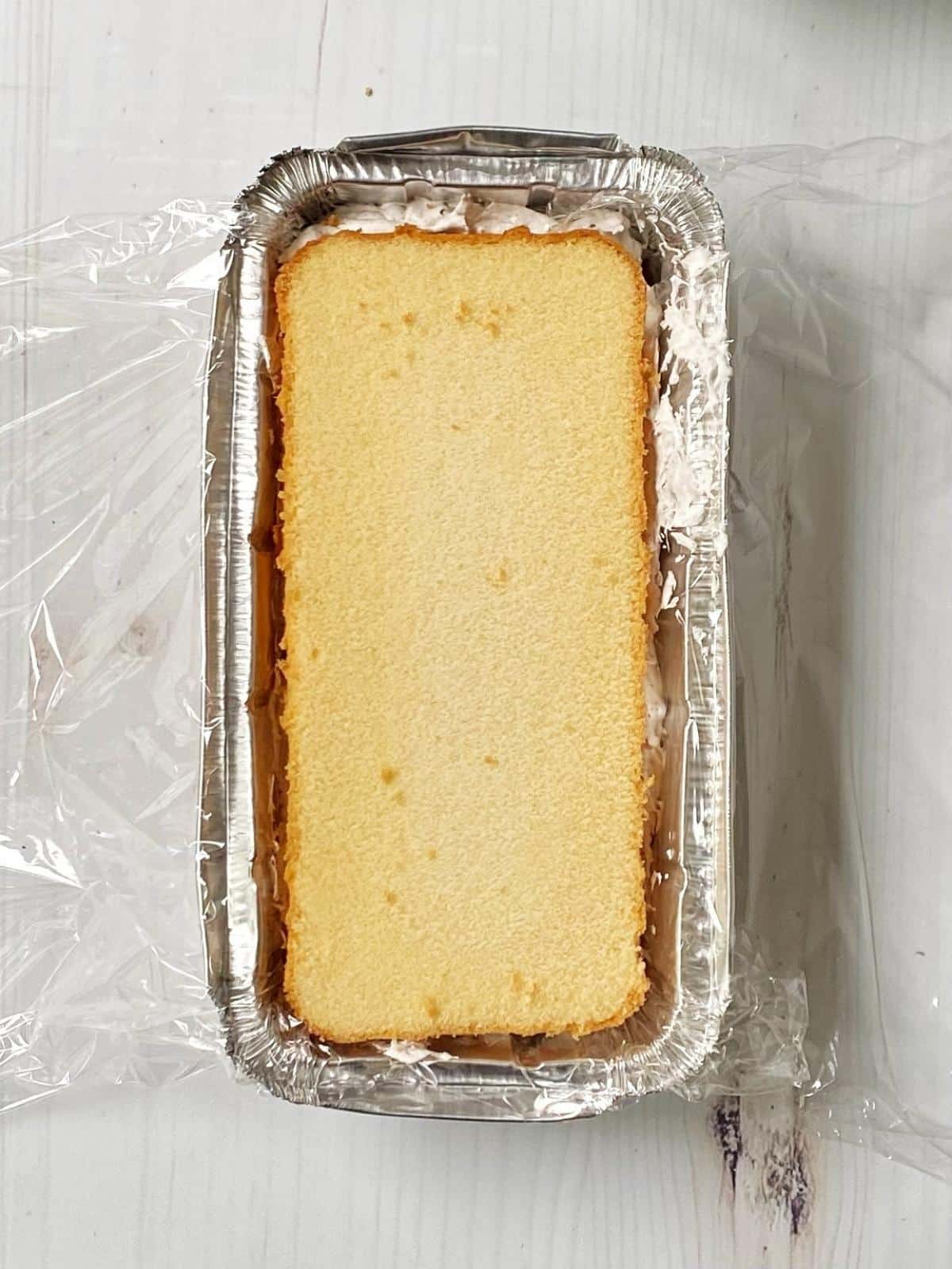 Adding second layer of cake in pan.