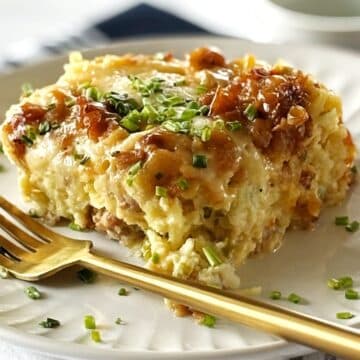 A fork on a plate with a serving of sausage casserole.