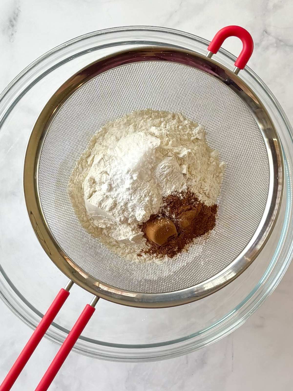Sifting flour, baking powder, baking soda, and salt into a bowl.