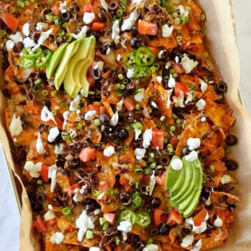 A sheet pan of nachos with toppings.