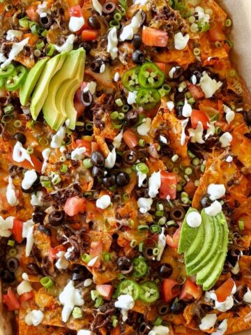 A sheet pan of nachos with toppings.