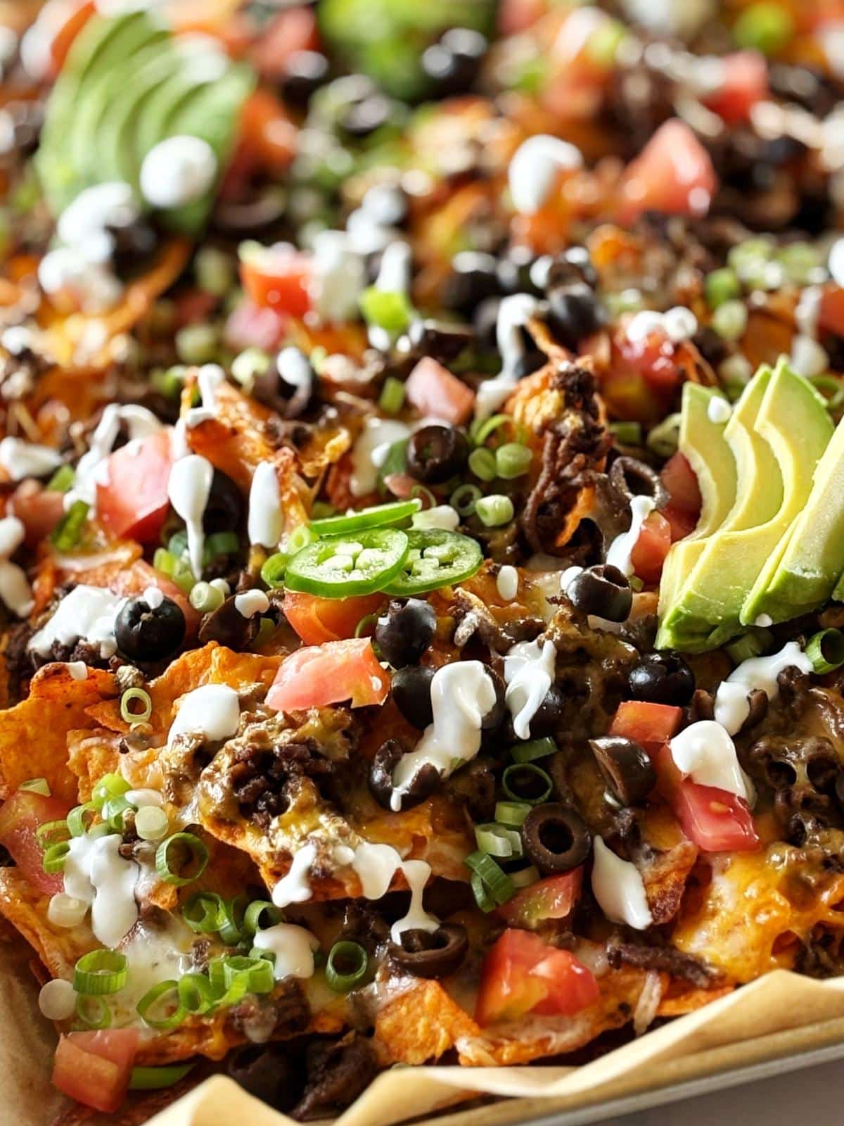 Nachos topped with crema, avocado, jalapeno, scallions, and black olives.