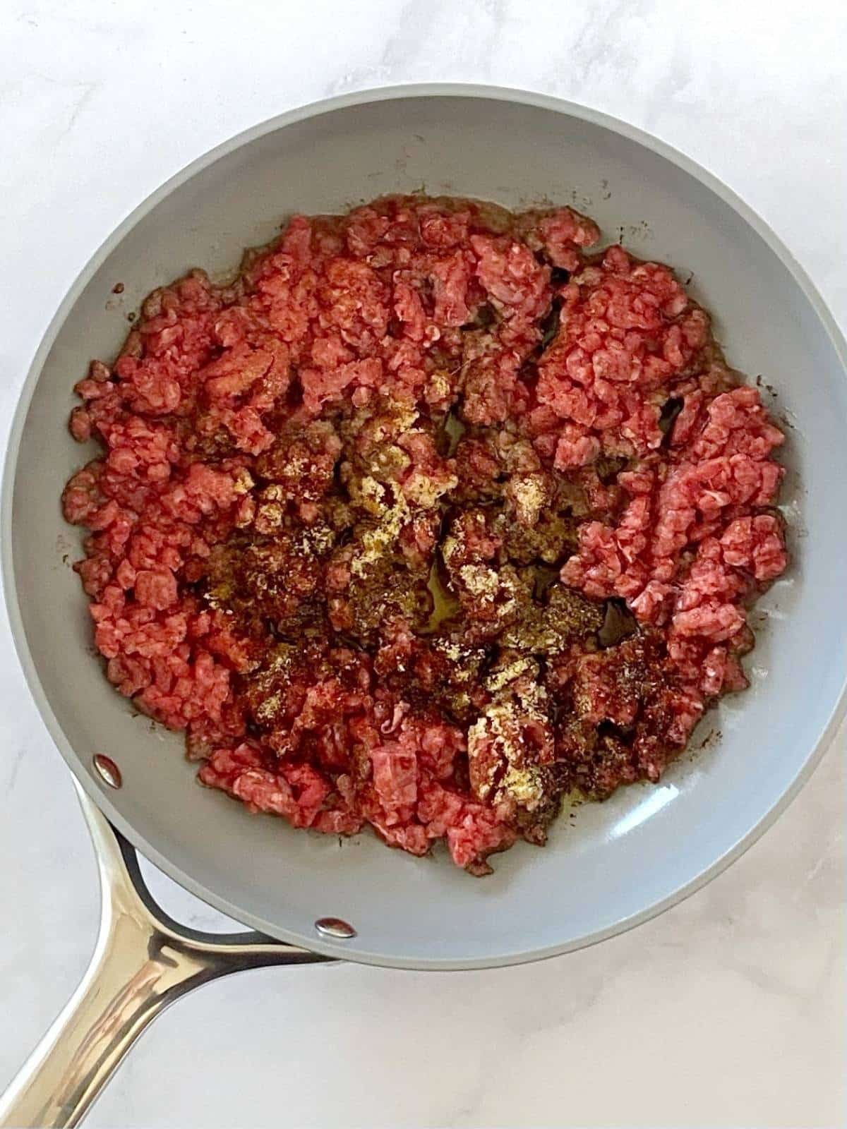 Ground beef and spices in a skillet.