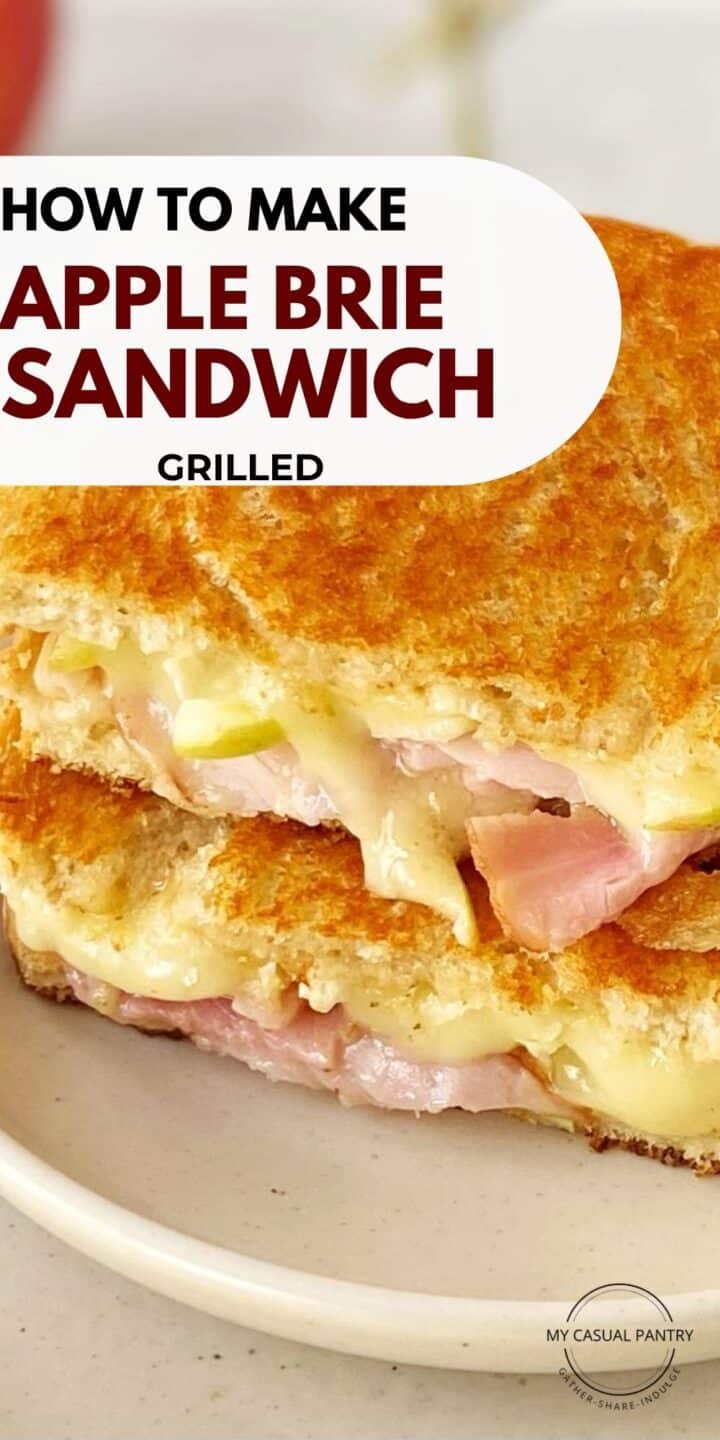 Grilled apple and Brie sandwich sliced in half on a plate.