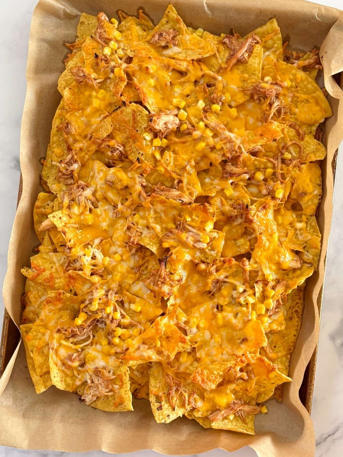 A sheet pan of baked bbq chicken nachos.