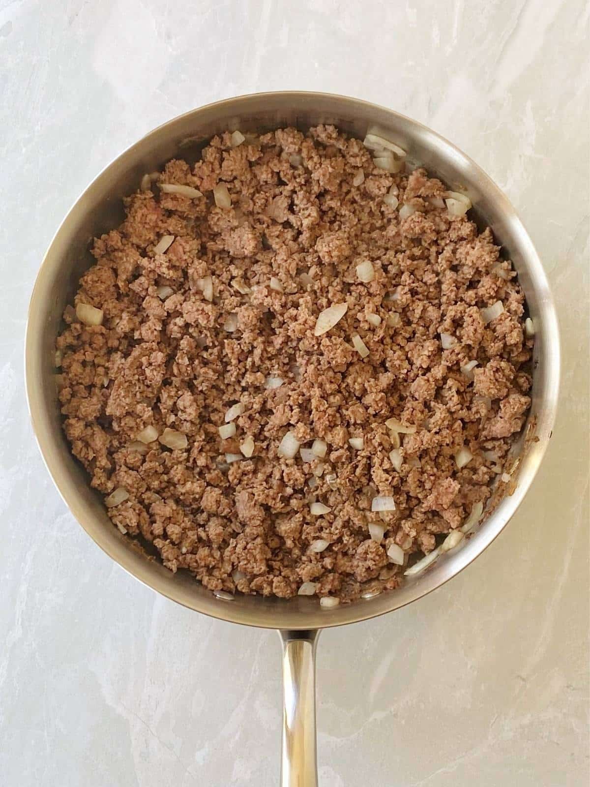 Cooked ground beef and onions in a skillet.