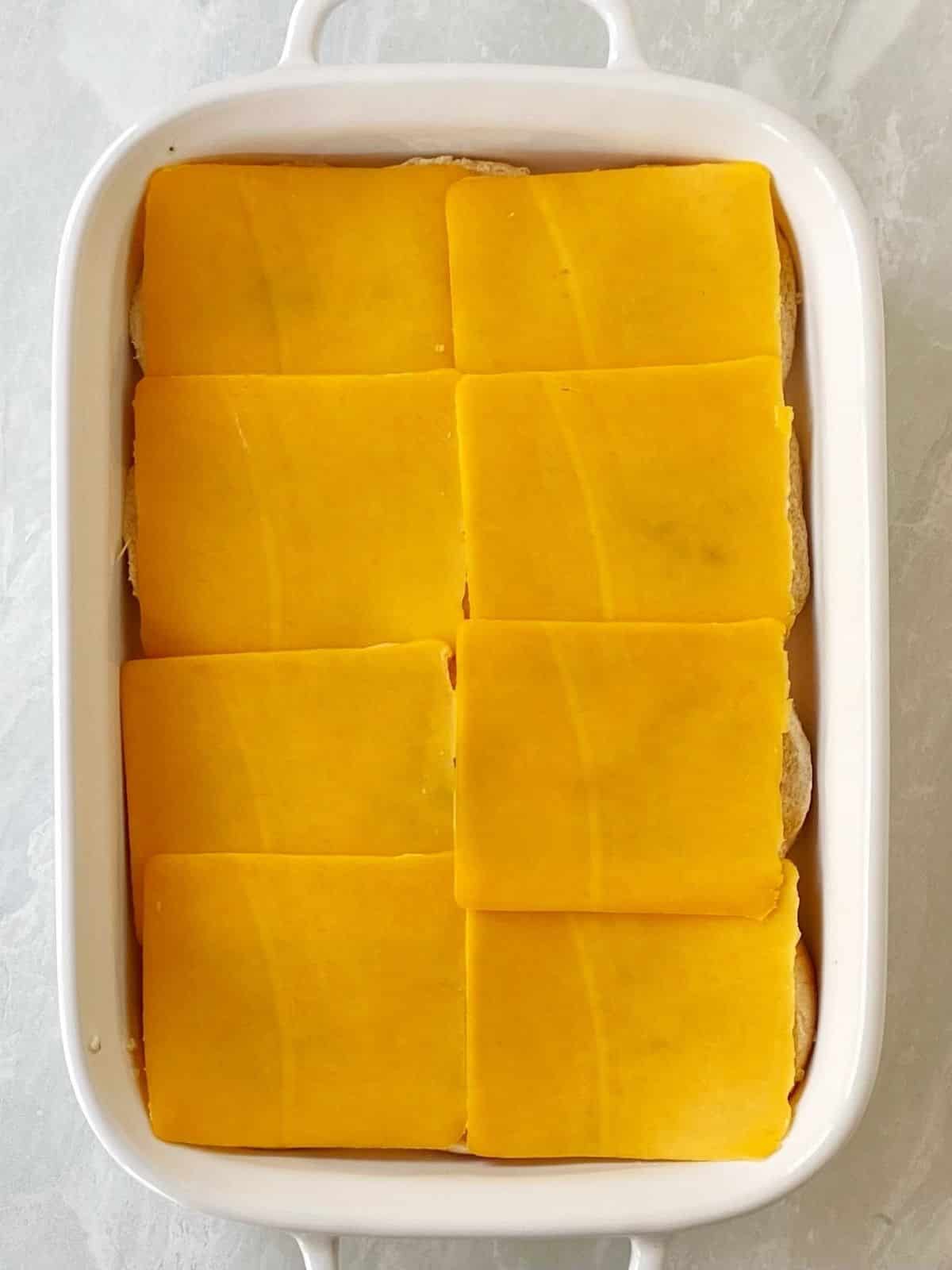 Layering cheese over the bottom buns.
