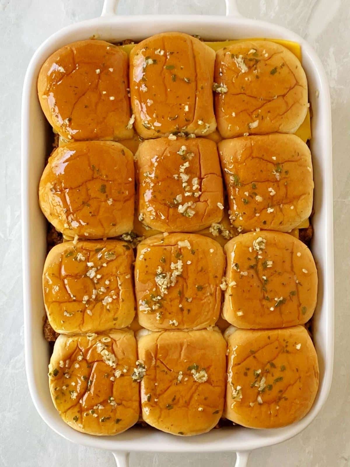 Top of buns placed on top of sliders and brushed with melted butter mixture.