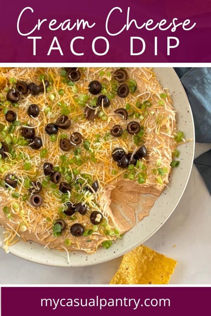 Taco dip spread on a platter with garnishes.