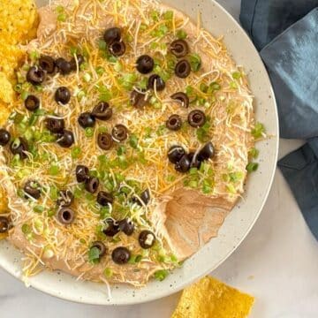 Taco dip on a serving platter with tortilla chips.