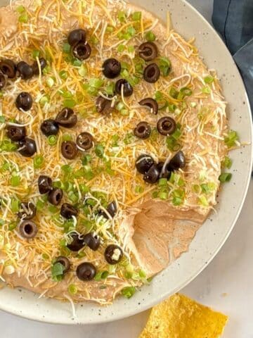 Taco dip on a serving platter with tortilla chips.
