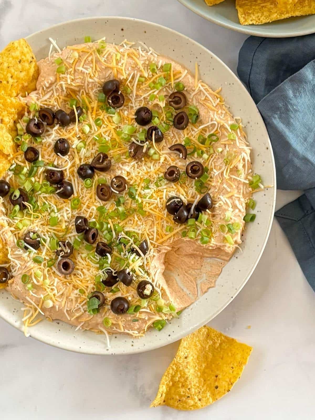 A platter of partially eaten dip with chips.