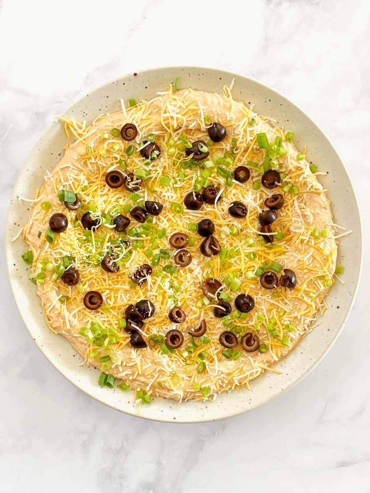 Dip topped with garnishes on a serving platter.