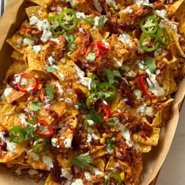 A sheet pan of nachos topped with a variety of garnishes.