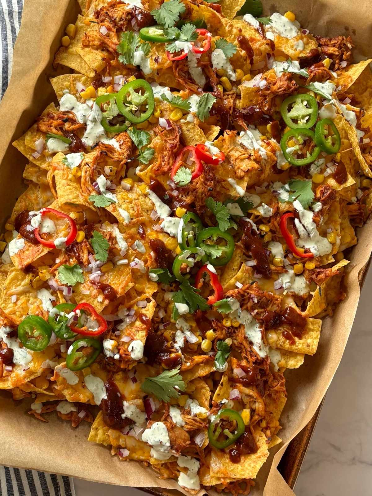 A sheet pan of nahocs topped with a variety of garnishes.