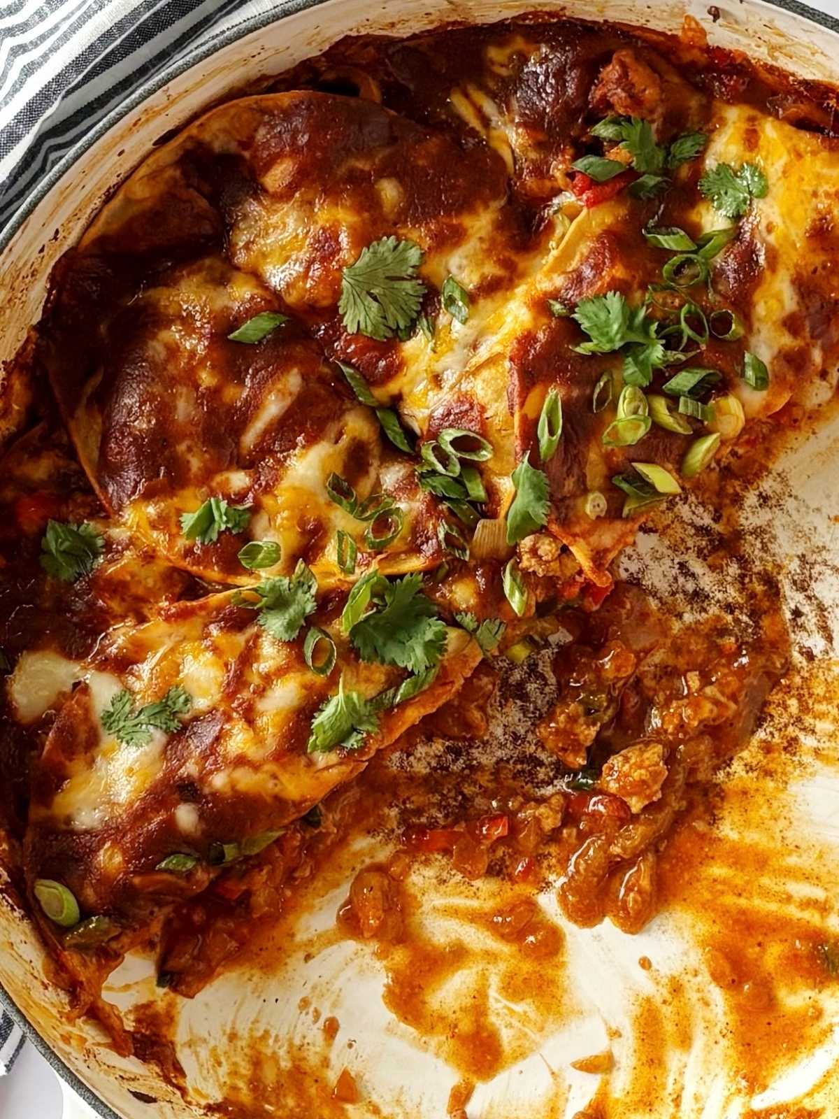 Partially eaten skillet of turkey enchiladas.