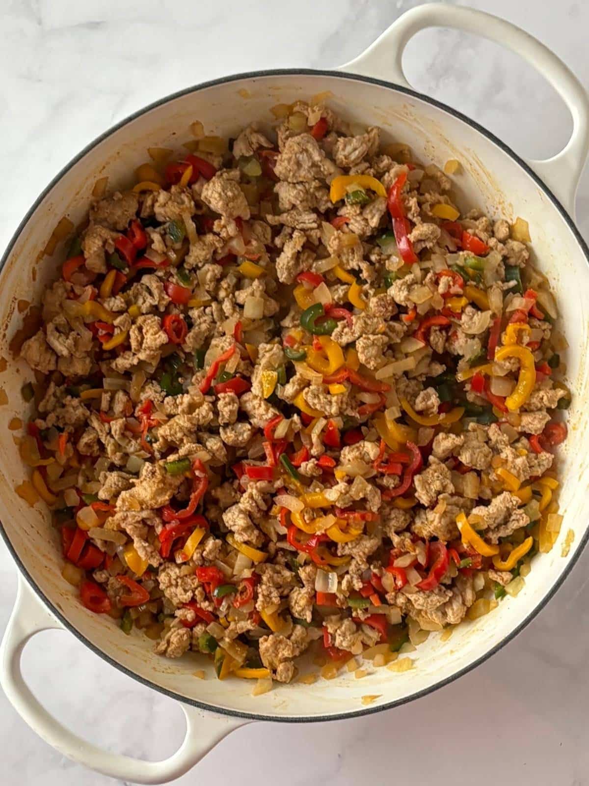 A skillet of cooked veggies and ground turkey.