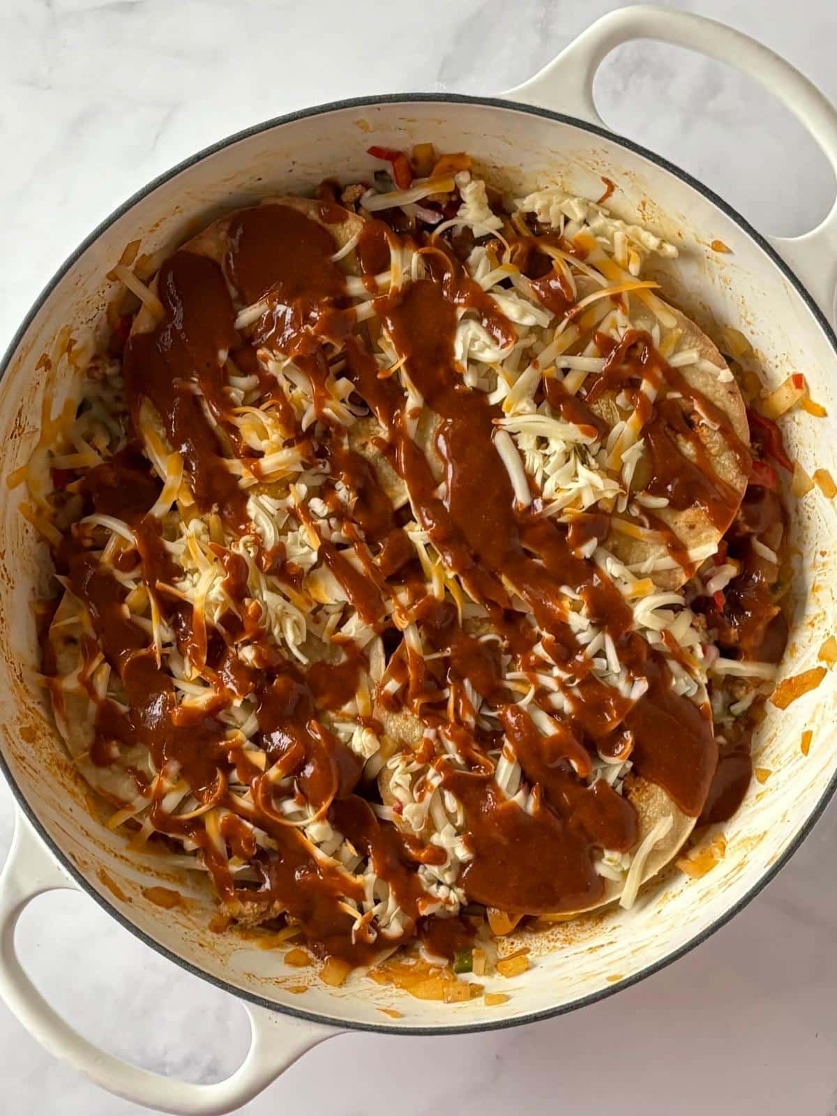 Layering turkey and veggie mixture with tortillas and cheese in a skillet.