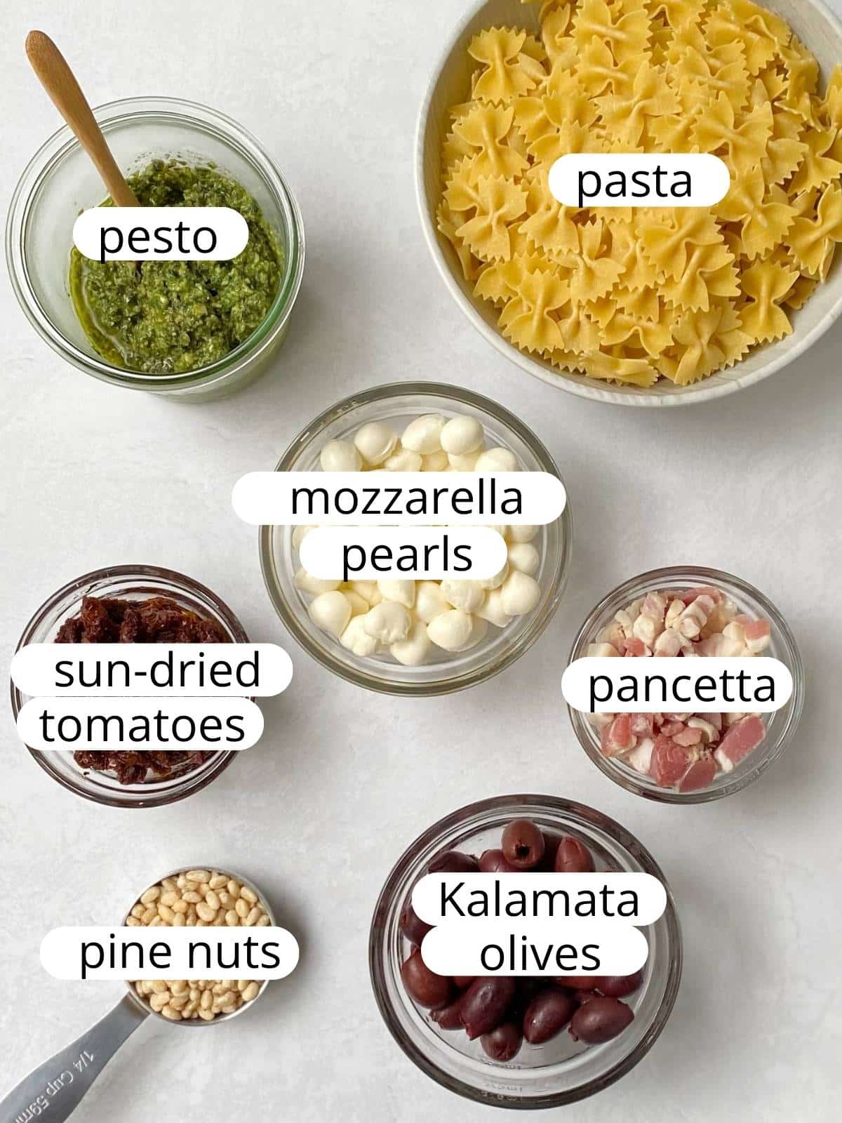 Ingredients for pesto pancetta pasta with olives and sun-dried tomatoes.
