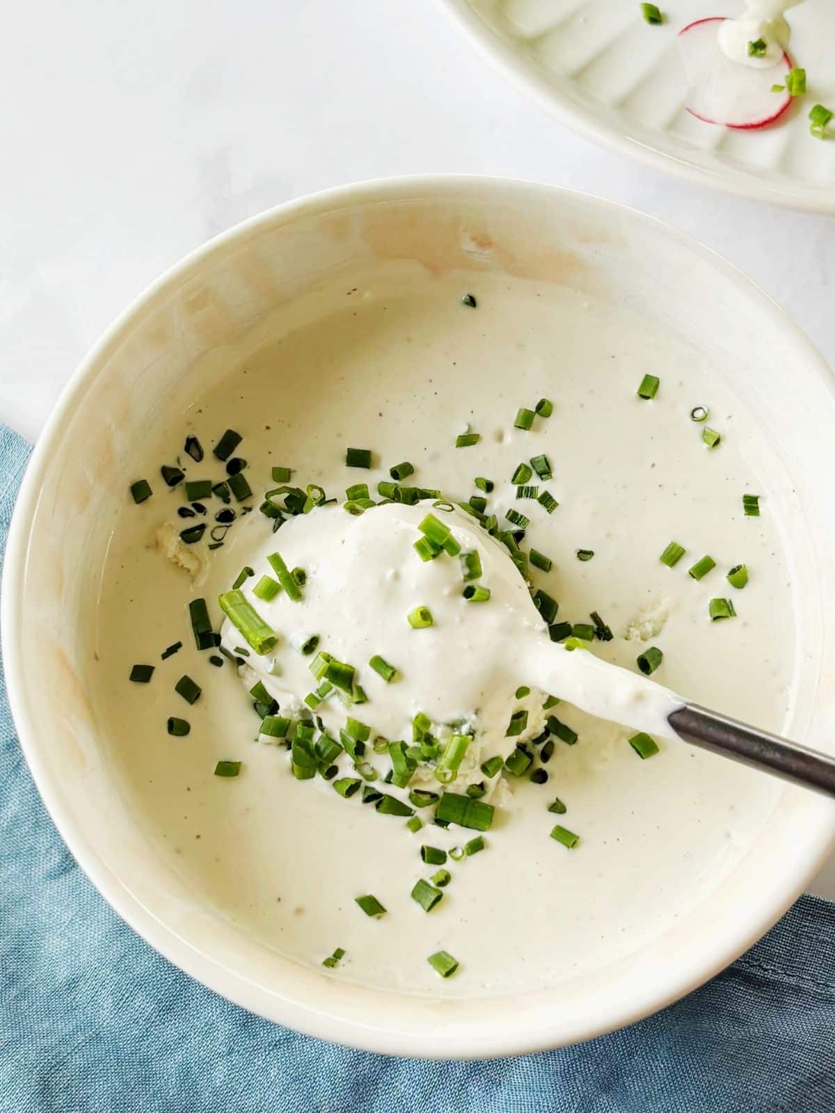 A spoon in a dish of blue cheese dressing.