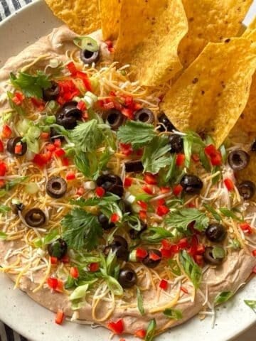 Taco dip on a platter with tortilla chips around the edge.