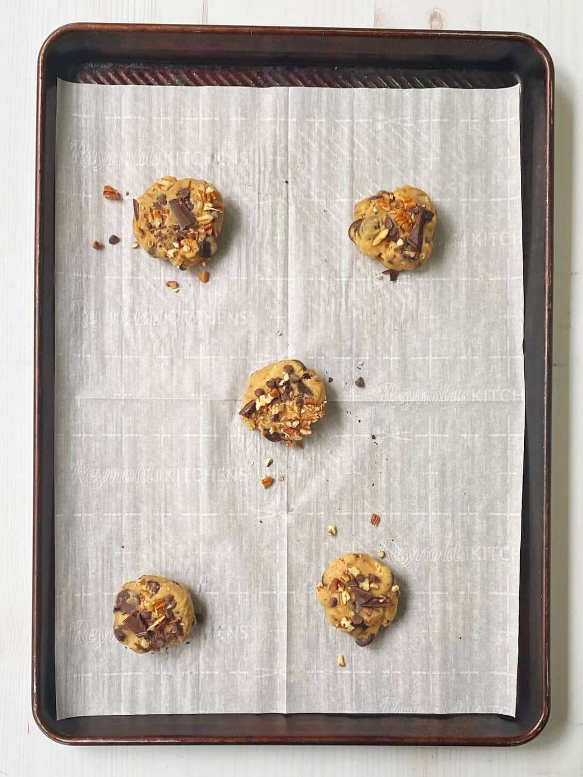 Cookie dough balls on a parchment-lined baking sheet.
