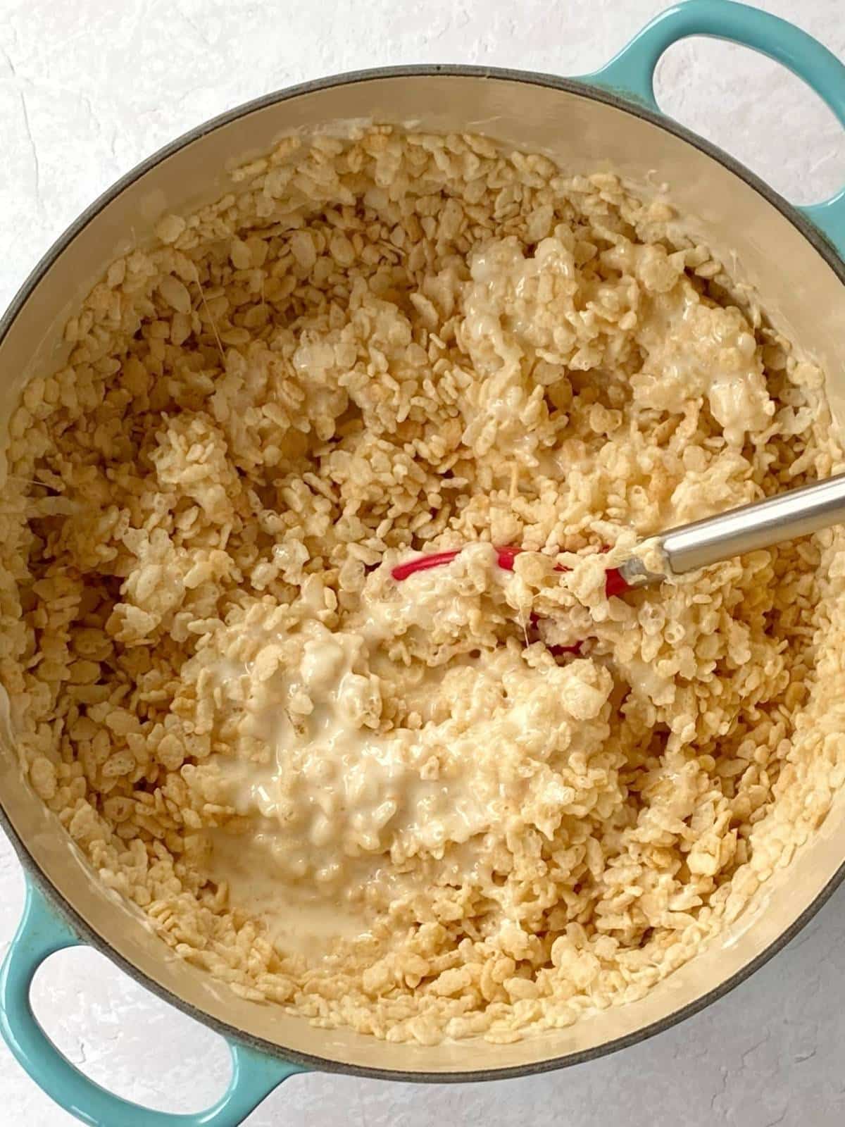 Adding cereal to melted butter and marshmallow mixture.